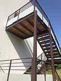 konstrukce s ocelovými profily, stupně a podesty z dřevěných desek, zábradlí se skleněnou výplníg