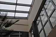 Skleněná střecha pokrývající skleník v kancelářské budově. Skleněné tabule umístěné na vrcholu pozinkovaného ocelového rámu namontovaného na střeše.