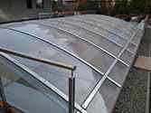 Střecha nad příjezdovou cestou do podzemního parkoviště. Polykarbonátové panely instalované na ocelové konstrukci s nerezovými plochami. Izolace mezi polykarbonátovými deskami a ocelovými profily pod nimi