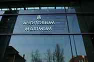 Logo z nerezové oceli Auditorium Maximum na skleněné stěně.