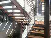 Ocelové schodiště, stupně z dřevěných desek, zábradlí se skleněnou výplní